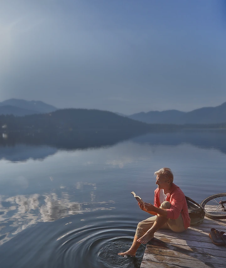 middle aged man sitting on a dock at a lake